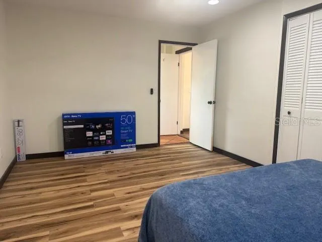 a view of an empty room with wooden floor and a fireplace