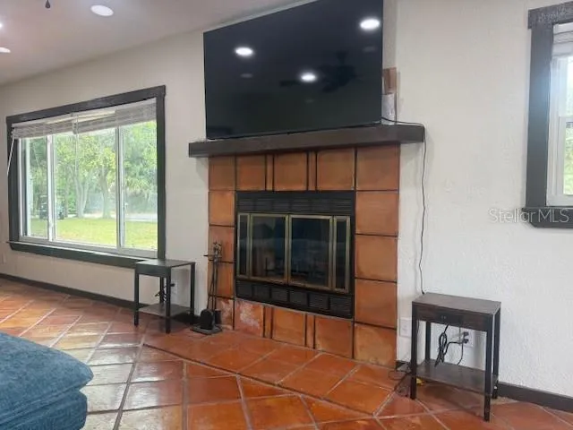 a living room with a fireplace furniture a ceiling fan and a window