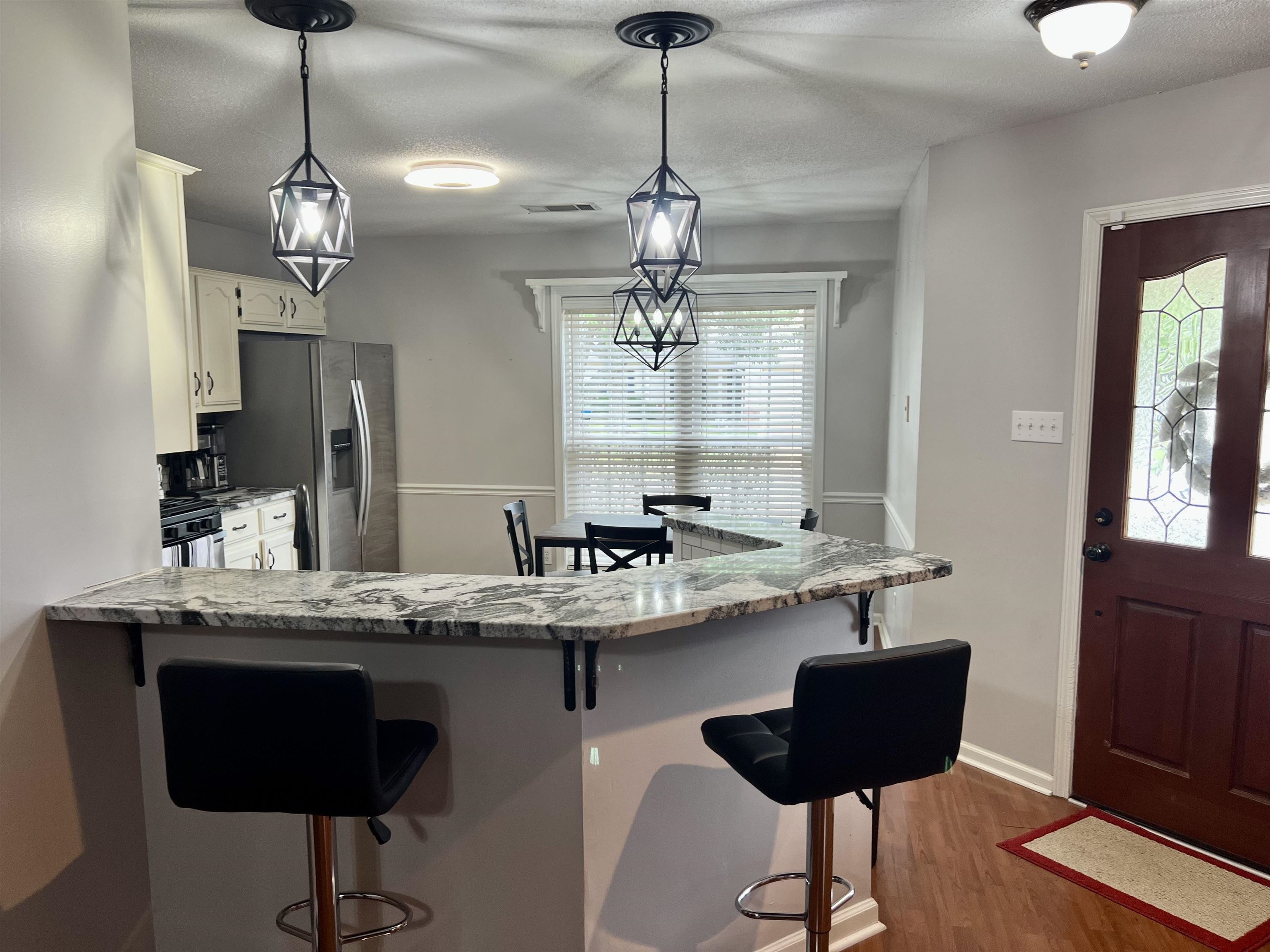 7429 Gingerhill Lane Bartlett, TN 38133 - Photo 3 of 20 a dining room with wooden floor a chandelier a wooden table and chairs