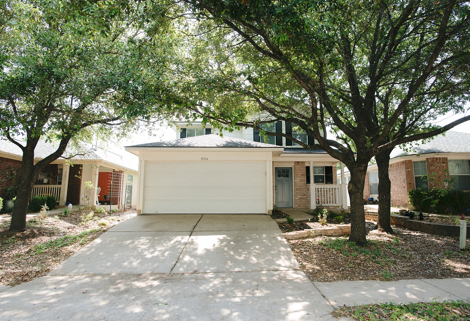 View of front of home with concrete driveway, brick siding, covered porch, and a garage