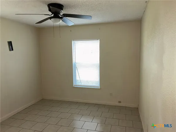 an empty room with a window and a fan