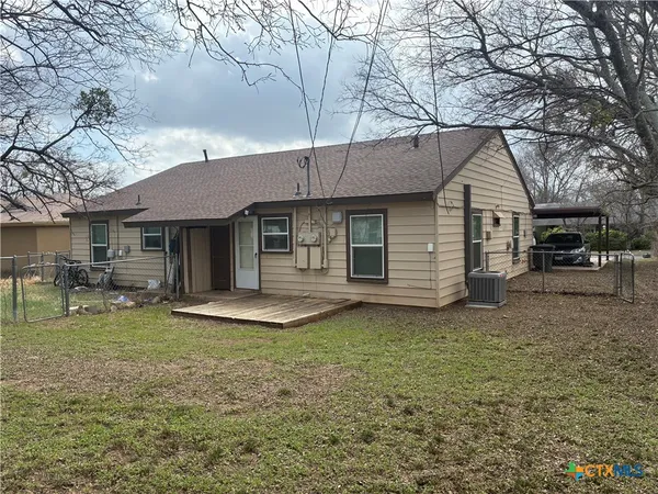 a front view of a house with a garden and trees