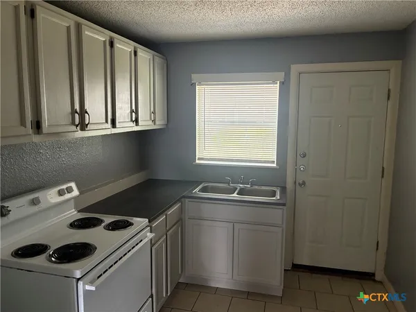 a kitchen that has a sink a stove and cabinets