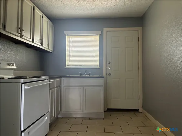 a kitchen with white cabinets and a stove top oven