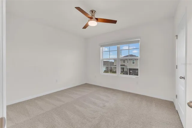 an empty room with a ceiling fan and window