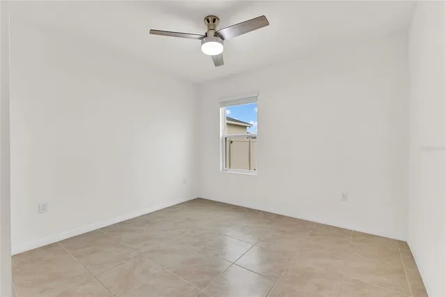 an empty room with a window and a ceiling fan