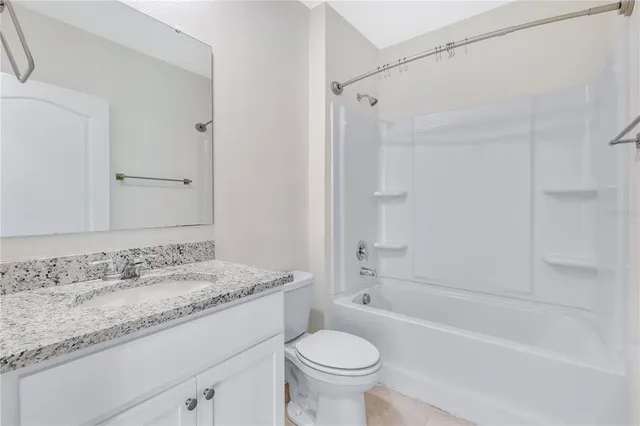 a bathroom with a granite countertop sink a toilet and shower