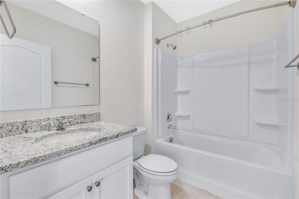 641 Talisi Loop St. Cloud, FL 34771 - Photo 14 of 40 a bathroom with a granite countertop sink a toilet and shower