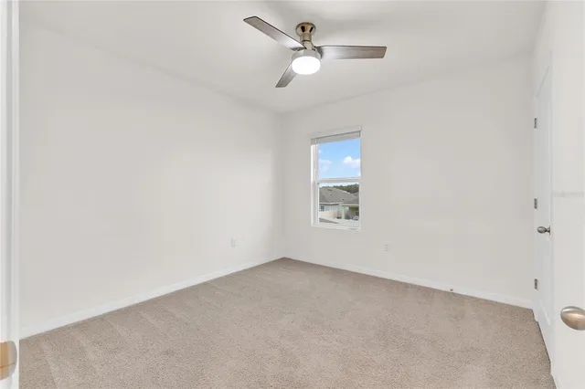 an empty room with a window and ceiling fan