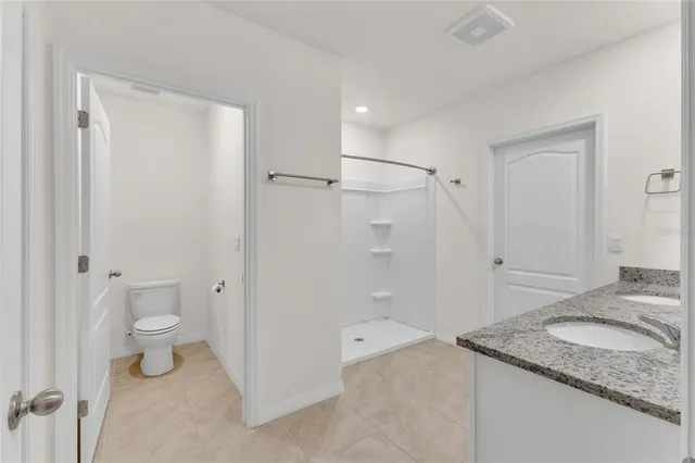 a bathroom with a granite countertop sink a toilet and shower