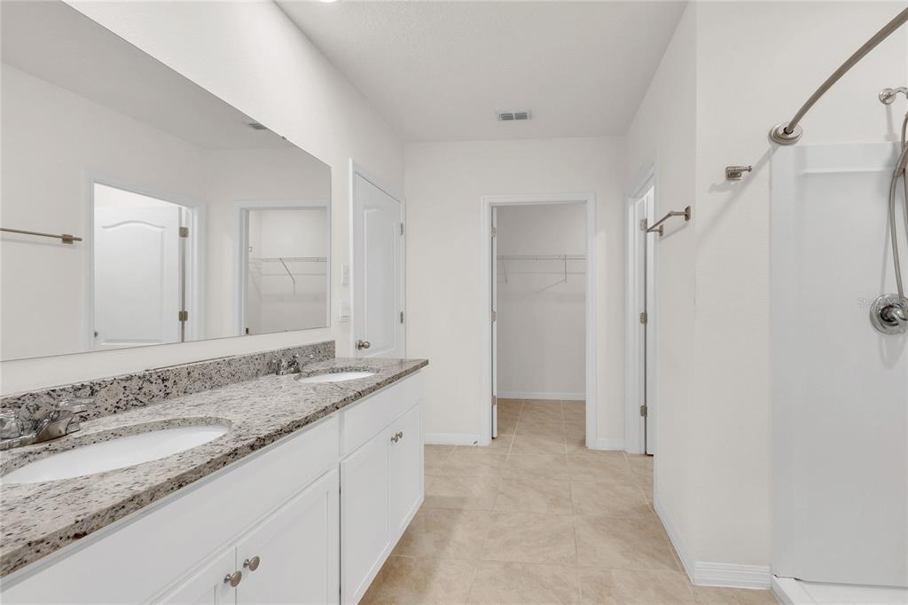641 Talisi Loop St. Cloud, FL 34771 - Photo 24 of 40 a spacious bathroom with a granite countertop sink and a mirror