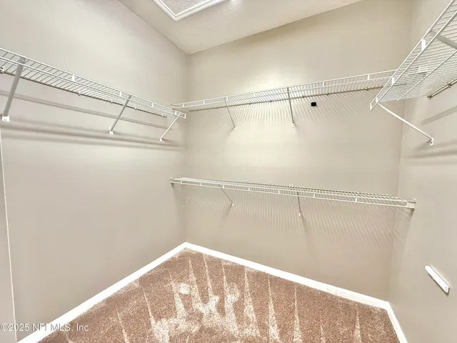 a view of an empty room and chandelier fan