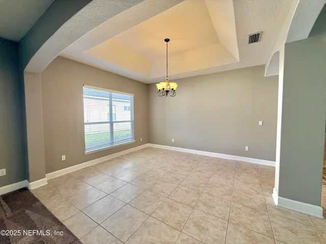 en empty room with windows and chandelier fan