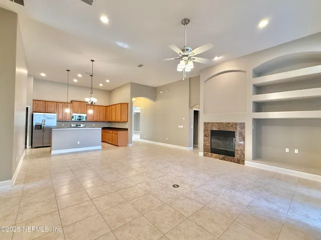 a view of an empty room with a chandelier fan