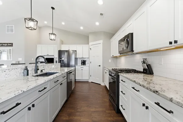 a kitchen with granite countertop a refrigerator a stove a sink and a refrigerator