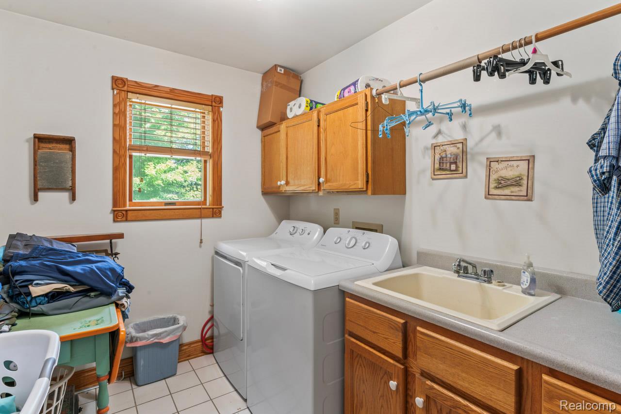 1591 Baldwin Road Lapeer, MI 48446 - Photo 14 of 46 Laundry room with light tile patterned flooring, cabinet space, and washing machine and clothes dryer