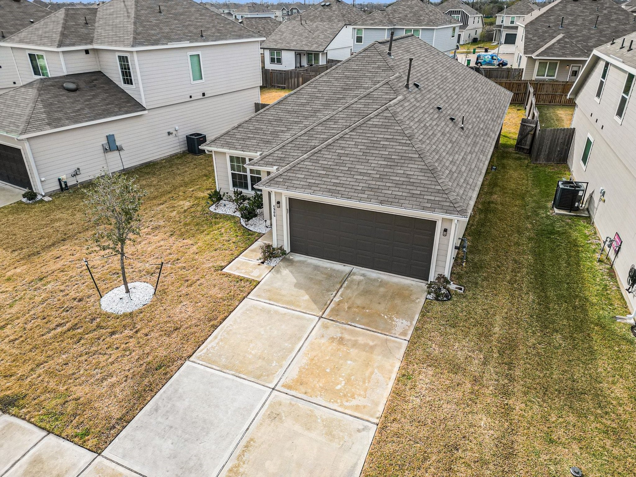 4906 Luke Matthew Drive Rosharon, TX 77583 - Photo 29 of 34 This aerial photo shows a modern single-story home with a two-car garage. The house features a neatly maintained lawn, a driveway, and is situated in a neighborhood with similar homes. The backyard is fenced, providing privacy.