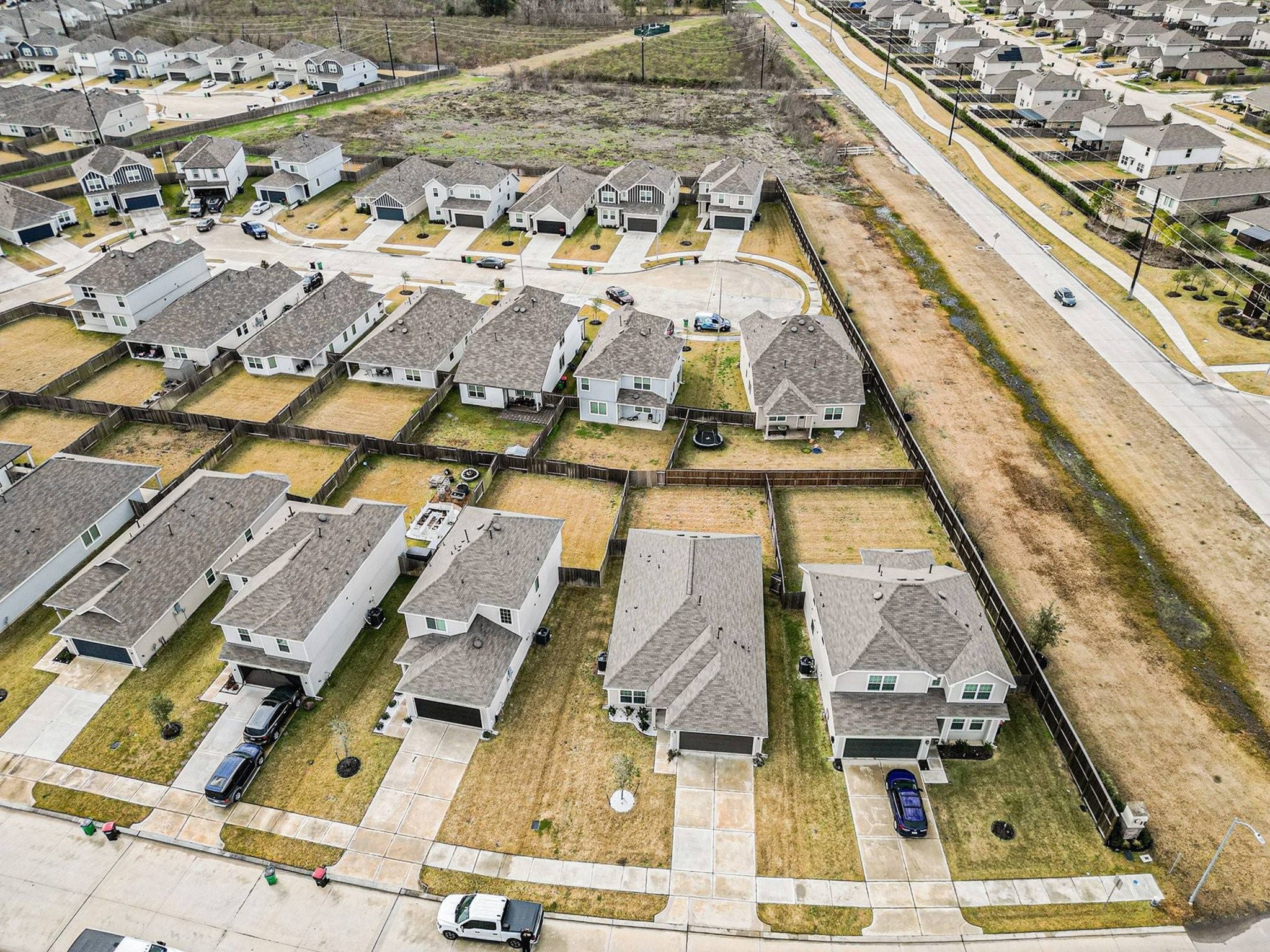 4906 Luke Matthew Drive Rosharon, TX 77583 - Photo 31 of 34 This aerial photo shows a suburban neighborhood with neatly arranged houses featuring gray roofs and fenced backyards. The streets are clean and well-maintained, and the area has easy road access. The layout suggests a quiet, family-friendly environment.