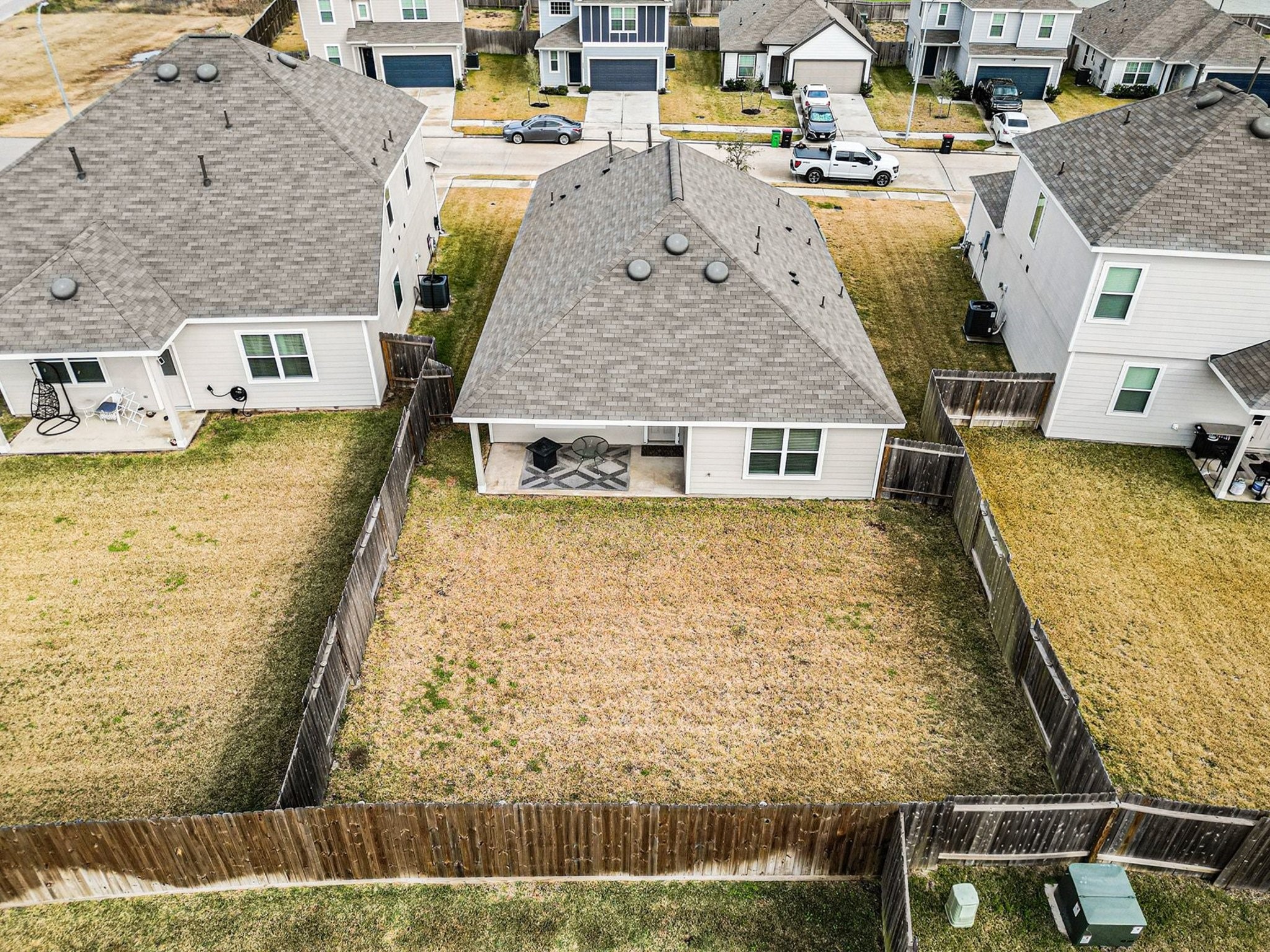 4906 Luke Matthew Drive Rosharon, TX 77583 - Photo 32 of 34 This aerial photo shows a single-story house with a fenced backyard, featuring a small covered patio. The yard is spacious, offering potential for landscaping or outdoor activities. The home is situated in a neighborhood with similar houses nearby.