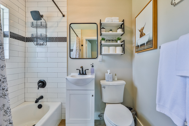 59 East 8680th Street South Sandy, UT 84070 - Photo 12 of 33 Bathroom featuring white subway tile surround with a black mosaic accent, black matte fixtures, and a white vanity with an integrated sink