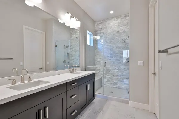 a bathroom with a double vanity sink a large mirror and shower
