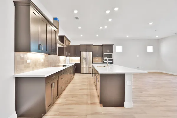 a large kitchen with stainless steel appliances kitchen island a large counter top and wooden floors