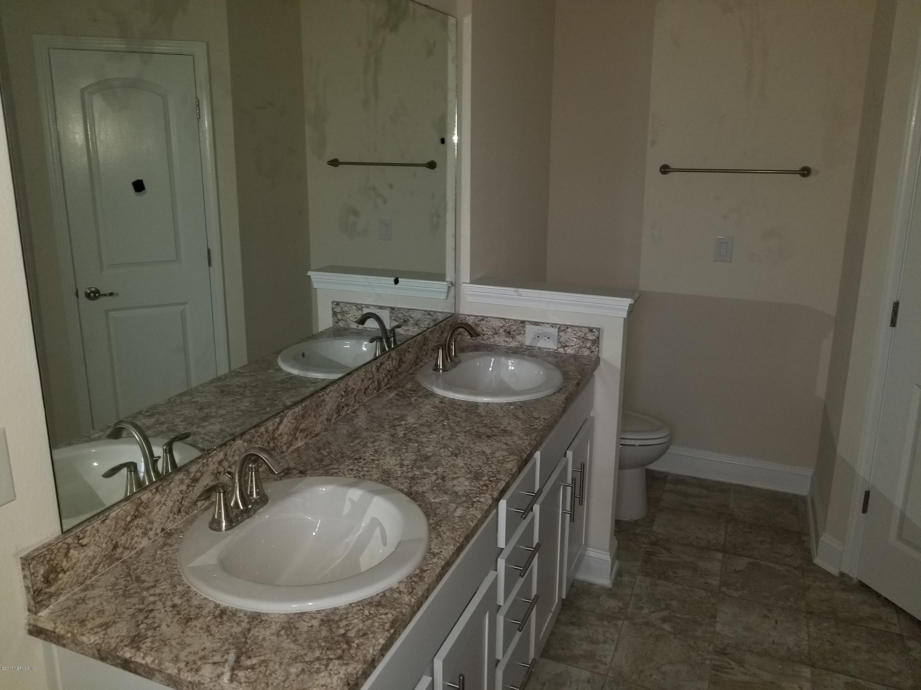 88051 Maybourne Road Yulee, FL 32097 - Photo 13 of 22 a bathroom with a granite countertop sink a toilet and a mirror