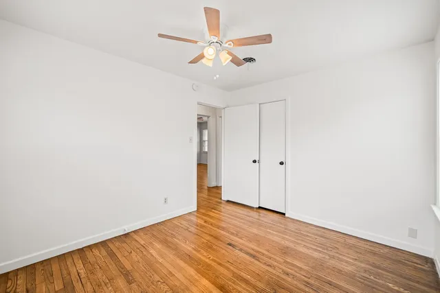 an empty room with wooden floor and ceiling fan