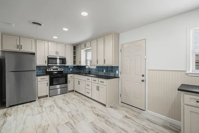 a kitchen with granite countertop a refrigerator sink and cabinets