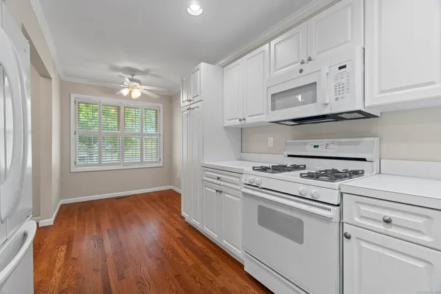 a kitchen with cabinets appliances wooden floor and a window