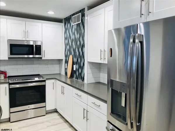 a kitchen with granite countertop a refrigerator stove and microwave