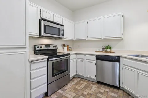 a kitchen with white cabinets stainless steel appliances and sink