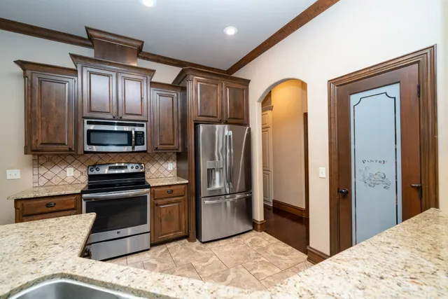 a kitchen with stainless steel appliances granite countertop a refrigerator and a stove top oven