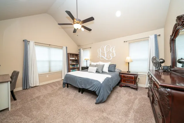 a spacious bedroom with a bed a dresser and a chandelier