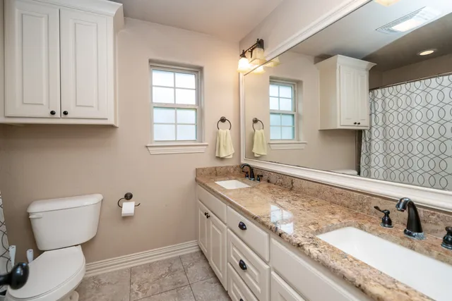 a bathroom with a granite countertop toilet sink and mirror