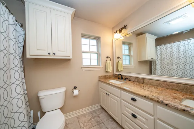 a bathroom with a granite countertop toilet sink and mirror