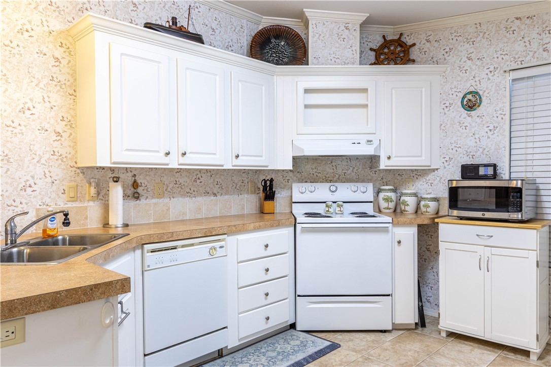 6171 98th Road Sebastian, FL 32958 - Photo 7 of 35 a kitchen with white cabinets and white appliances