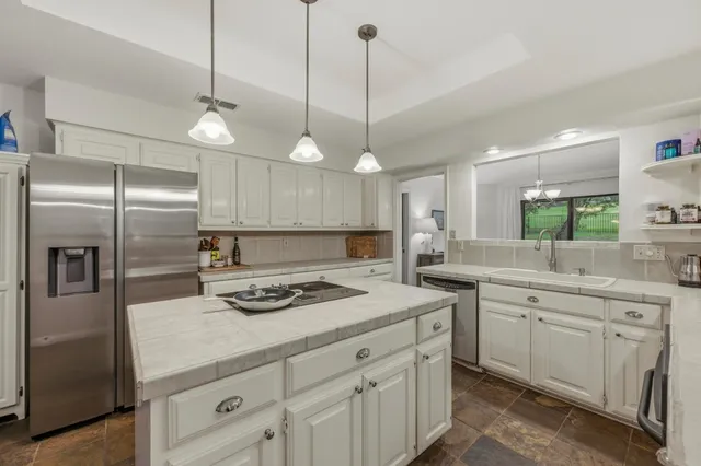 a kitchen with a sink a refrigerator a stove and white cabinets