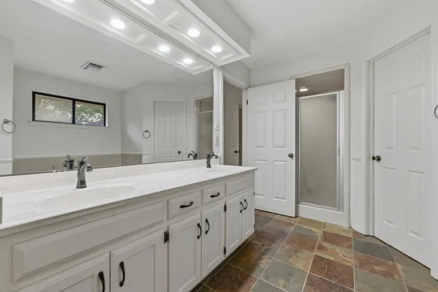 a spacious bathroom with a double vanity sink a mirror and a