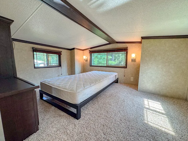 a bedroom with a bed a dresser and windows