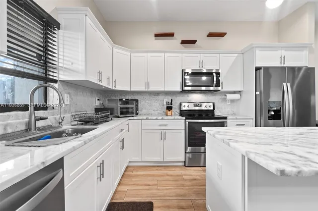 a kitchen with stainless steel appliances granite countertop a sink a stove a refrigerator and cabinets
