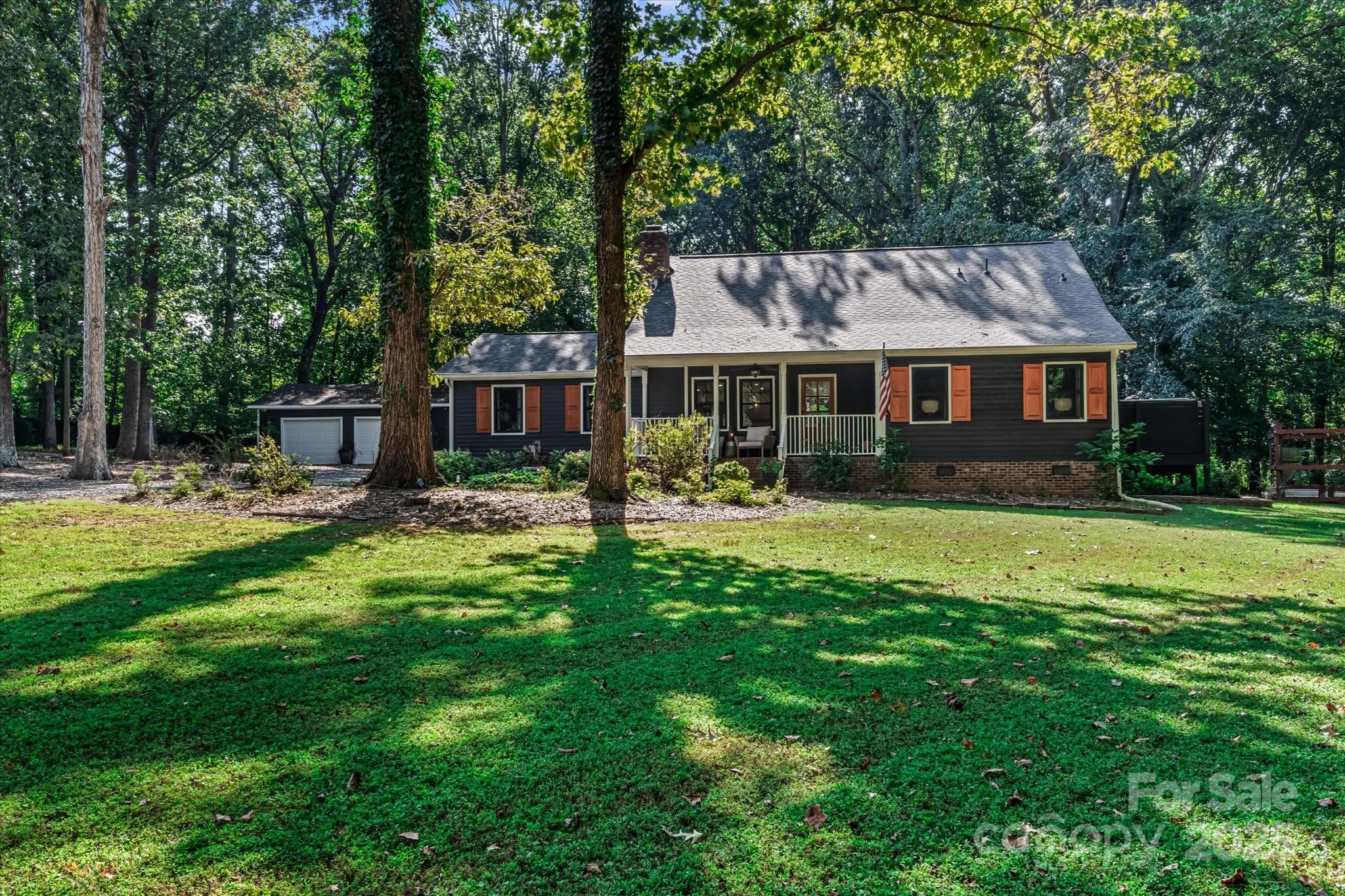 a front view of a house with a garden and trees