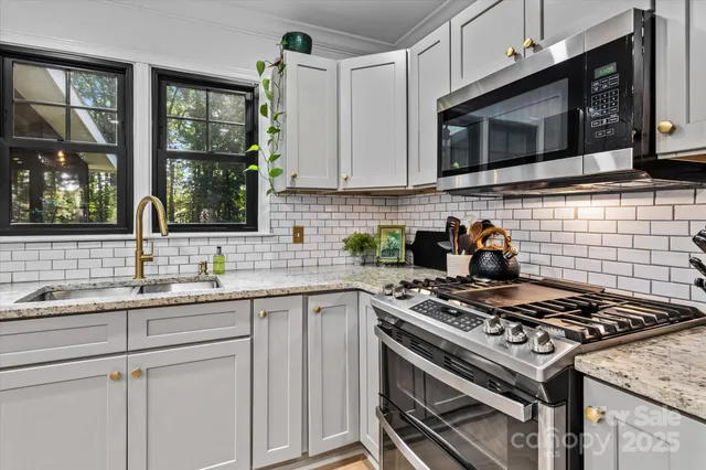 a kitchen with stainless steel appliances granite countertop a sink stove top oven and microwave