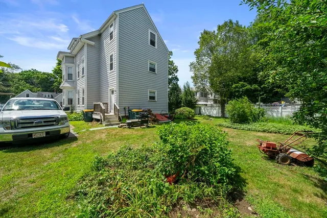 a backyard of a house with lawn chairs plants and tree