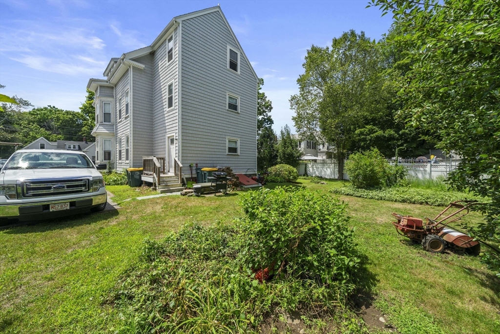 96 Plymouth Street, Unit 2 Abington, MA 02351 - Photo 2 of 9 a backyard of a house with lawn chairs plants and tree