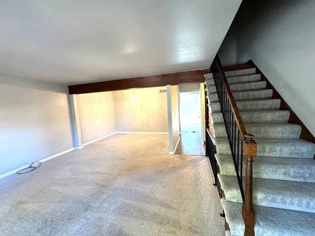 a view of an empty room with wooden floor and stairs