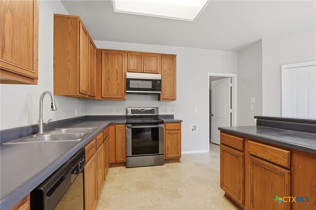 8716 Starview Street Temple, TX 76502 - Photo 11 of 36 Kitchen detail showcasing the built-in oven and microwave alongside warm wood cabinetry.