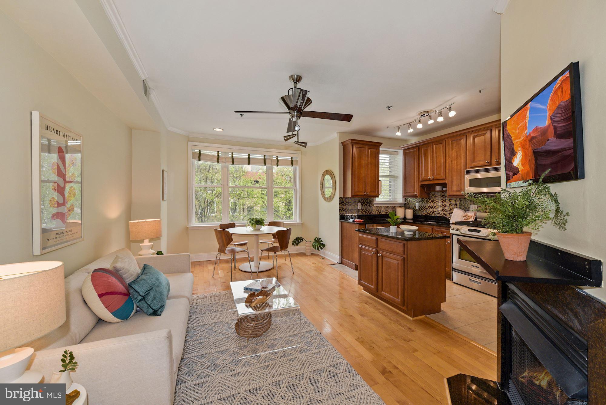 a living room with stainless steel appliances granite countertop furniture a rug kitchen view and a large window