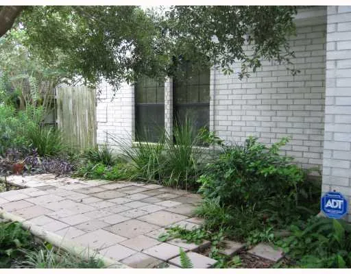 a pathway of a house with potted plants and large trees