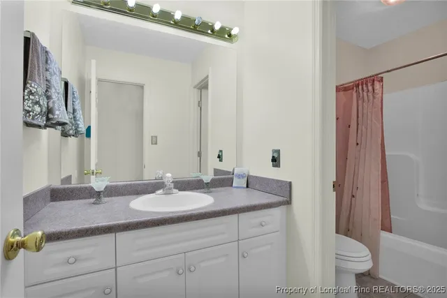 a bathroom with a granite countertop sink a toilet a mirror and shower